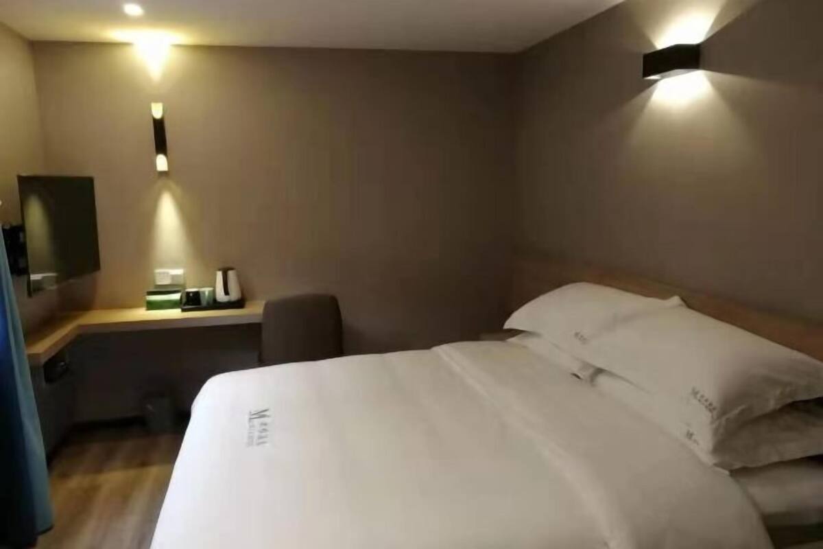 Et hotelværelse med seng, sengebord og et lille skrivebord med stol.