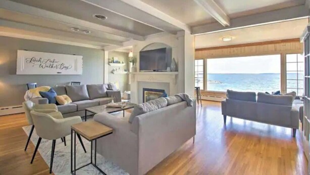 Un salón amplio con chimenea, un sofá grande y vista al mar.