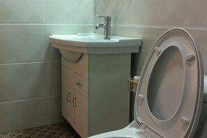 A bathroom with a toilet, sink, and cabinet. - Kunming Sanxin Serviced Apartment Hotel (Binjiang Junyuan) (Kunming)