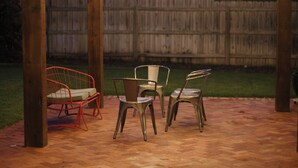 Eine Terrasse im Freien mit einer Holz-Pergola, Lichterketten und Metallstühlen.
