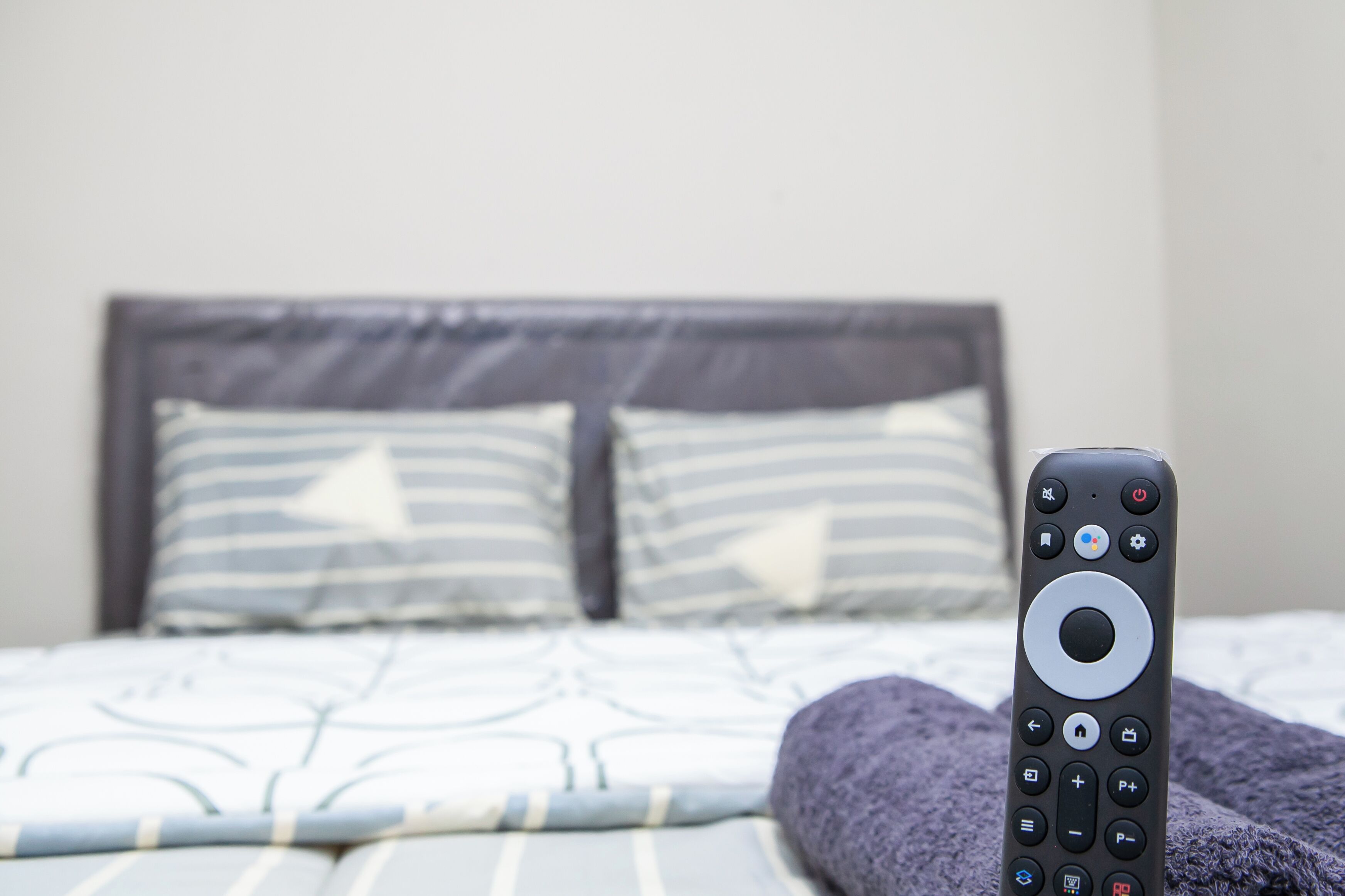 Un lit avec une télécommande posée dessus.