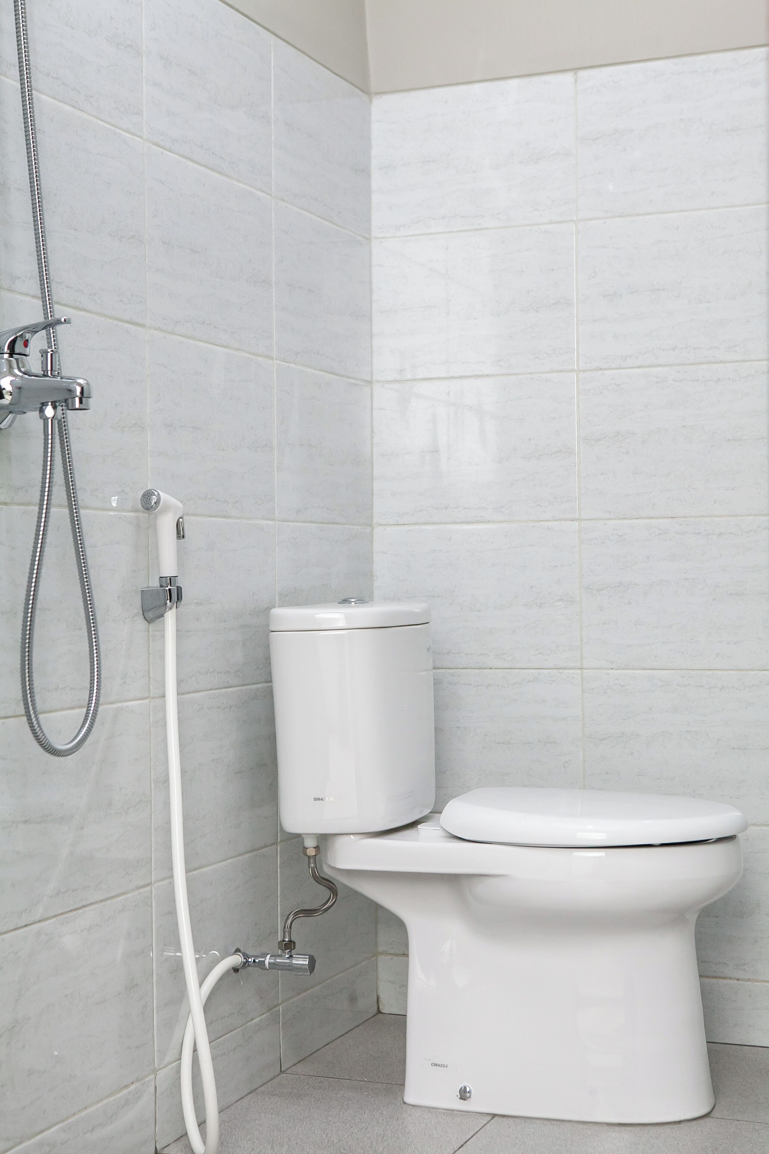 A modern bathroom with a toilet, a shower, and a white tiled wall.