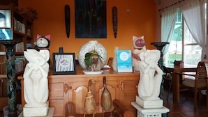 A room with a wooden cabinet displaying various sculptures and framed pictures. - Bali Hostel (Hualien)