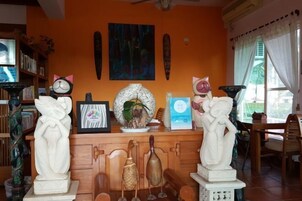 Quarto com um armário de madeira exibindo várias esculturas e quadros emoldurados.