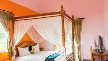 Una cama con dosel, ropa de cama blanca, cabecera de madera y cortinas translúcidas.