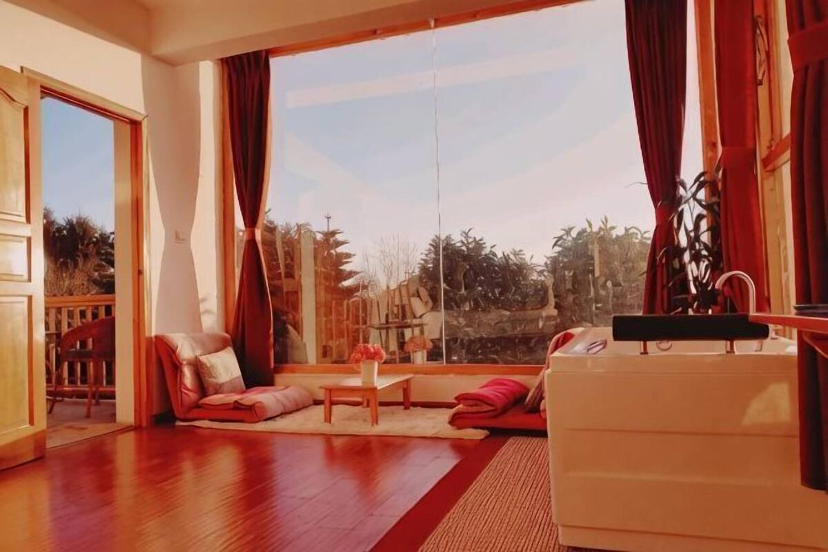 A room with a large window, a sofa, a small table, and a white cabinet.