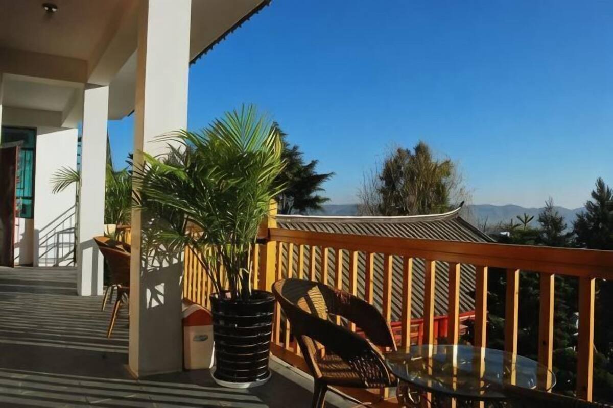 A balcony with a wooden railing, potted plants, and outdoor furniture.