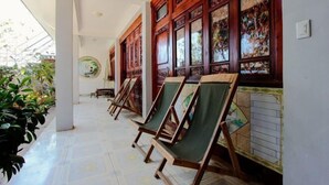 A corridor with wooden-framed windows and green canvas chairs. - Gospel Hostel (Dali City)