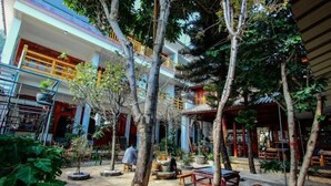 A courtyard with a dining area, potted plants, and a building with balconies. - Gospel Hostel (Dali City)