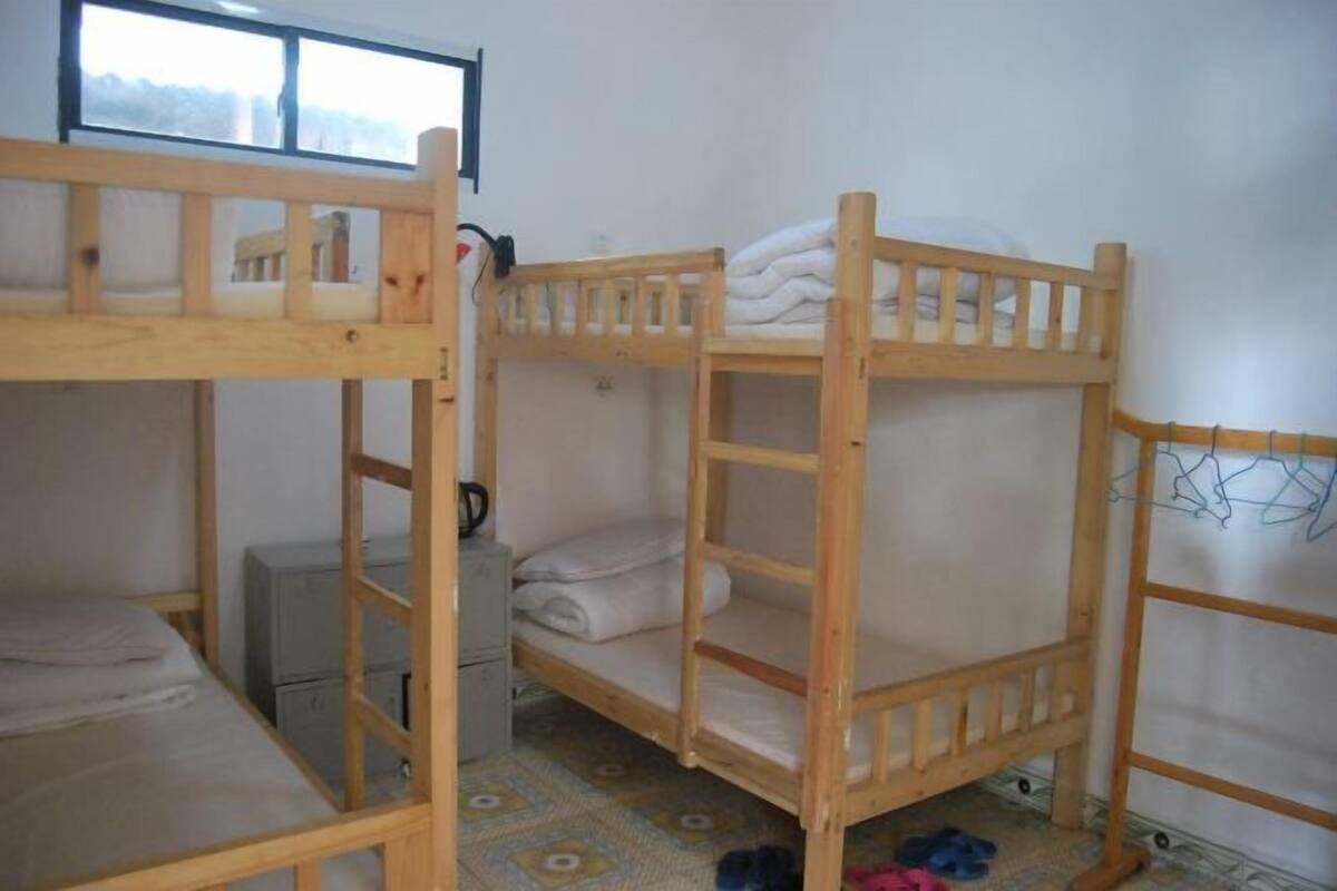 A bunk bed room with a window, a small desk, and a patterned floor.