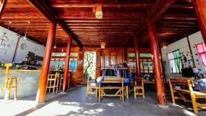 A wooden interior with a high ceiling, wooden beams, and a central seating area with benches. - Gospel Hostel (Dali City)