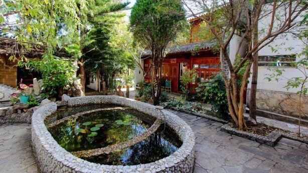 A courtyard with a stone-lined pond, surrounded by trees and traditional architecture. - Gospel Hostel (Dali City)