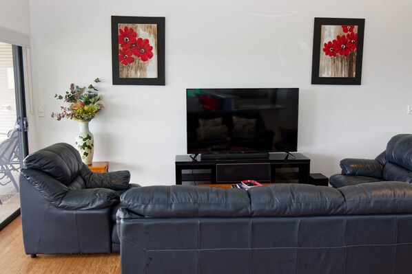 A living room with a TV, two sofas, and a vase with flowers. - Dorper Downs (Baskerville)