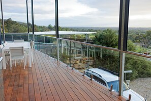 A wooden deck with a glass railing overlooking a scenic landscape. - Dorper Downs (Baskerville)