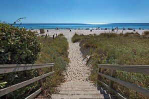 A wooden staircase leading to a beach with a clear blue sky.