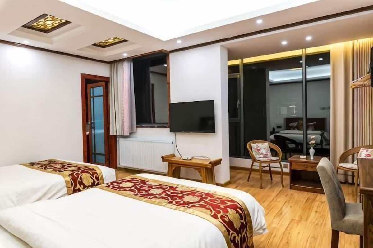 Une chambre d’hôtel avec deux lits, un bureau, une chaise, une télévision et une porte coulissante donnant sur un balcon.