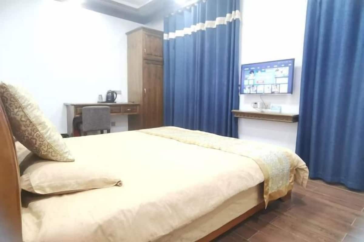 Une chambre à coucher avec un lit, un bureau, une chaise, une armoire et un téléviseur fixé au mur.