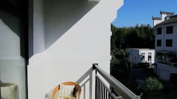 A balcony with a wicker chair and a white wall.