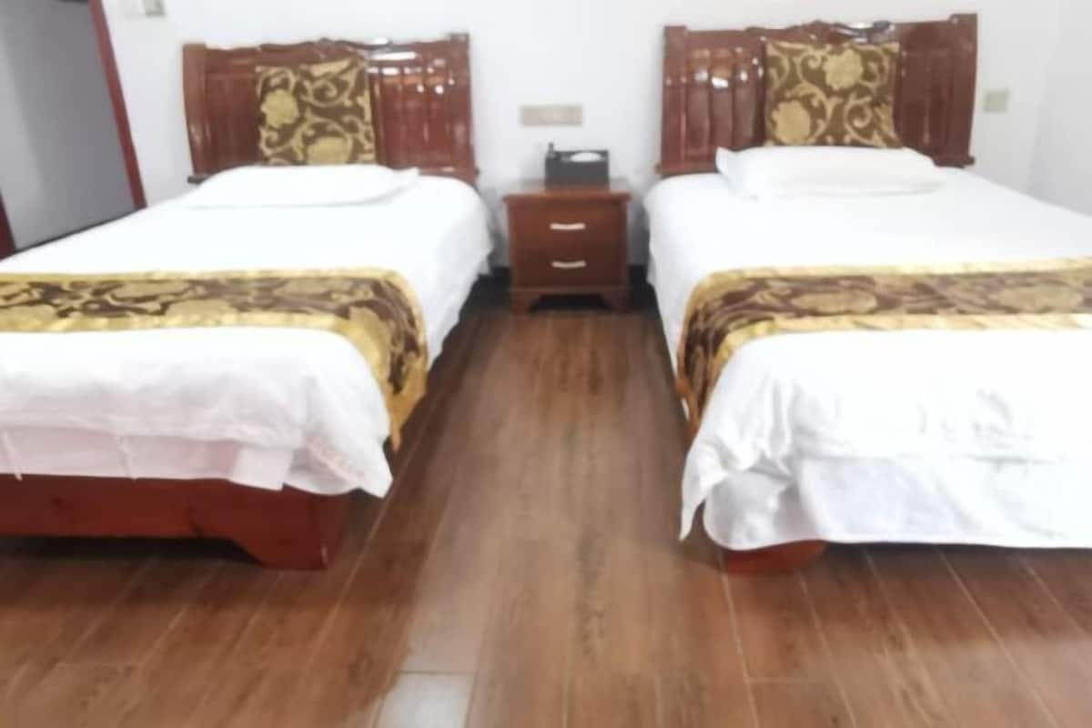Une chambre d’hôtel avec deux lits en bois, chacun agrémenté d’une couvre-lit à motifs et d’une tête de lit assortie.