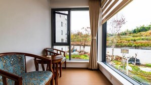 A room with a sofa, a small table, and a window with a view of a lake and greenery. - Yi Xuan Ju Deluxe Lnn and Suites (Yi County)