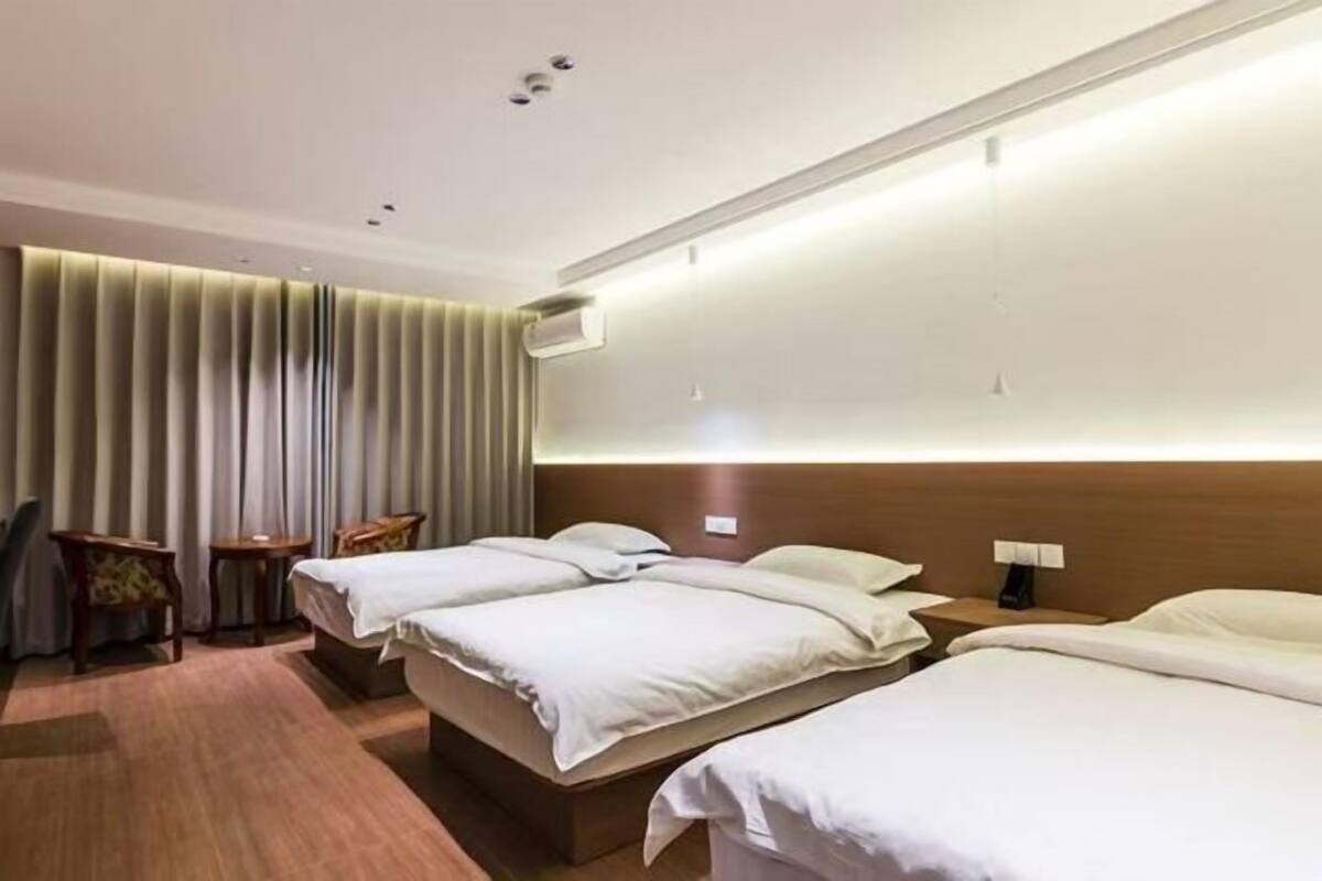 Une chambre d’hôtel avec deux lits, une tête de lit en bois, une petite table et une chaise.