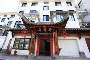 Un bâtiment traditionnel chinois, avec un toit recouvert de tuiles, des poutres en bois et des décorations rouges.