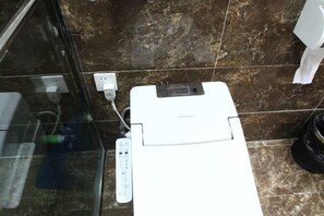Een badkamer met een wit toilet, een douchecabine van glas en een vloer betegeld met marmer.