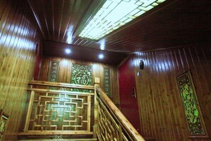 Un escalier en bois orné de sculptures complexes, un mur en bois avec des panneaux décoratifs et un plafond doté d’une lucarne.