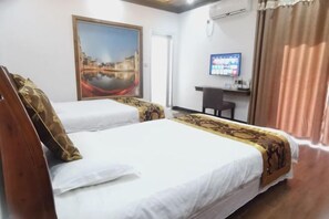 Een hotelkamer met twee bedden, een bureau, een televisie en een schilderij van een stadsbeeld.