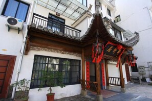 A traditional building with a tiled roof, a wooden balcony, and a red decorative archway. - Yi Xuan Ju Deluxe Lnn and Suites (Yi County)