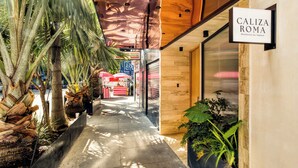 A corridor with a sign for 'Caliza Roma' and a storefront in the background. - Caliza Roma | Exclusive Residence w/Private Garden (Ciudad de México)