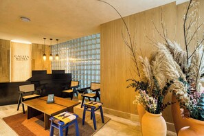 A reception area with a wooden reception desk, black chairs, and a large vase of pampas grass.