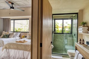 Relax in comfort with a large bed, glass-enclosed shower, and ceiling fan.