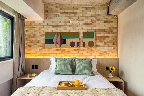 Experience a cozy retreat with a brick-patterned headboard, wooden nightstand, and comfortable white linens.