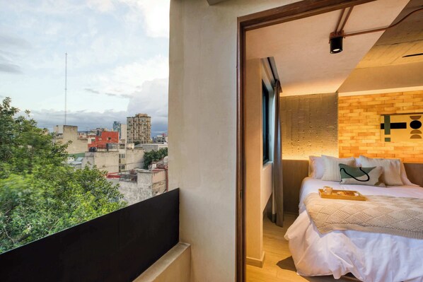 A bedroom with a city view, a brick accent wall, and a bed with pillows and a tray.