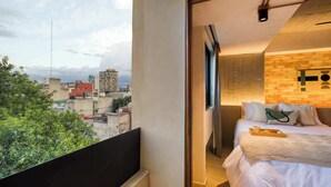 Une chambre avec vue sur la ville, un mur d’accent en briques et un lit agrémenté d’oreillers et d’un plateau.