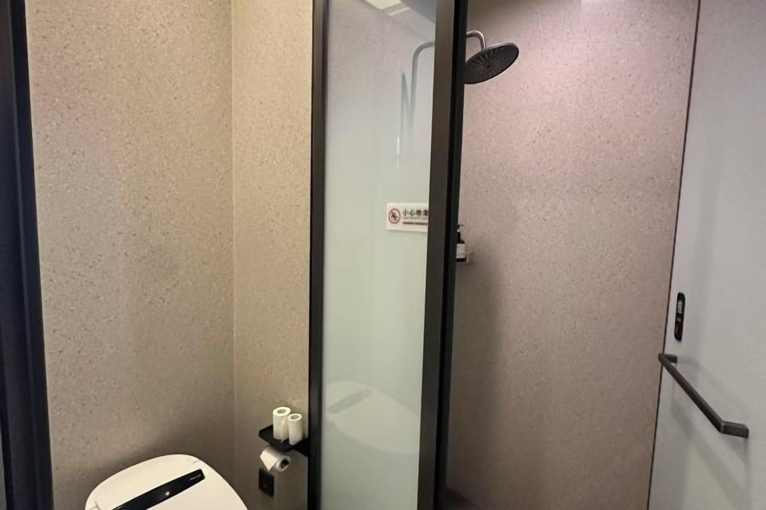 A bathroom with a toilet, a glass shower enclosure, and a towel rack.