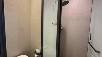 A bathroom with a toilet, a glass shower enclosure, and a towel rack.
