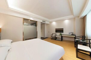 Una habitación de hotel con una cama grande, un escritorio con una silla, un televisor y una puerta que da a un baño.