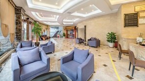 Un vestíbulo amplio con asientos modernos, una recepción y una escalera que conduce a los pisos superiores.