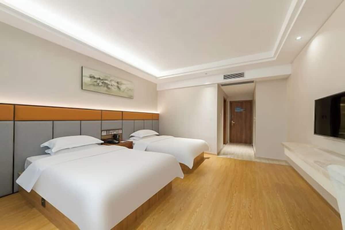 A hotel room with two beds, a flat-screen TV, a painting on the wall, and a wooden floor.