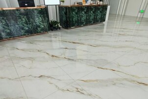 Un área de recepción de mármol con dos mostradores, uno con encimera de mármol verde y otro con una encimera de mármol más claro.