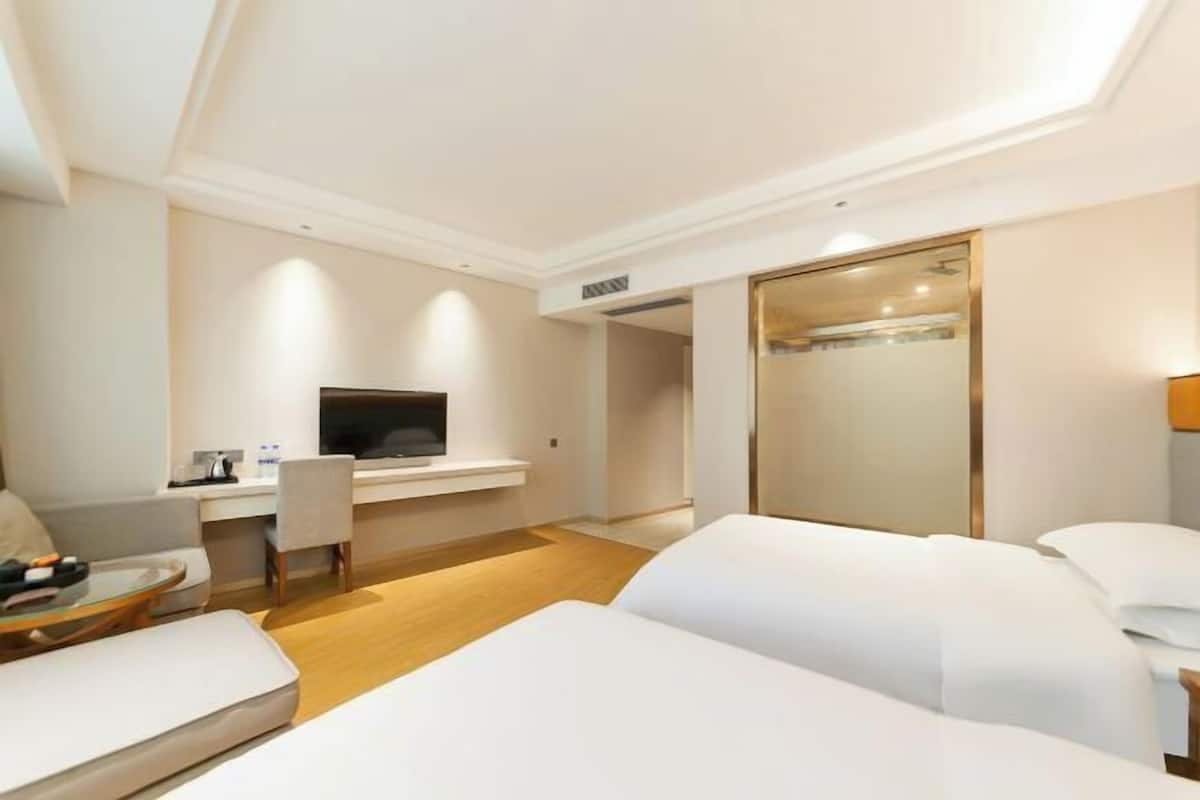 A hotel room with a bed, a desk with a television, a chair, and a mirror.