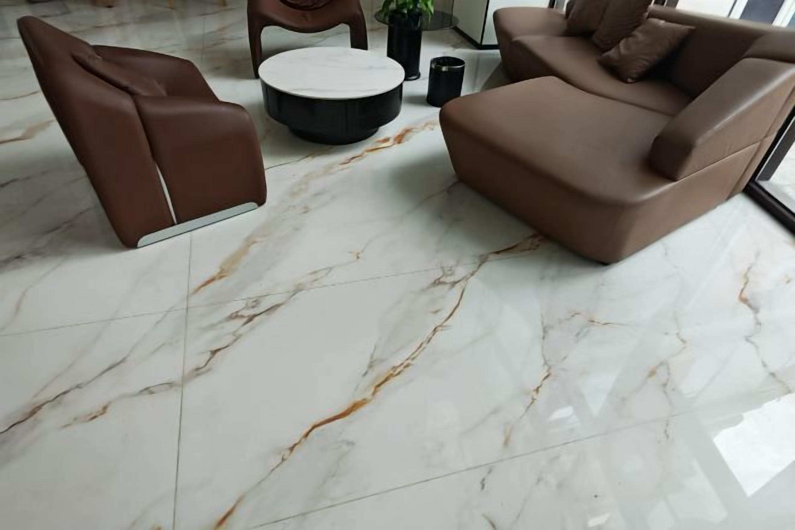 A modern living room with a brown sofa, a brown armchair, and a round coffee table on a marble floor.