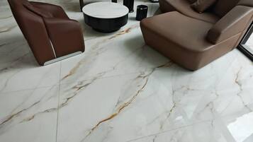 A modern living room with a brown sofa, a brown armchair, and a round coffee table on a marble floor.
