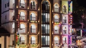 Un edificio de varios pisos con ventanas y balcones de arco, iluminado por luces cálidas.