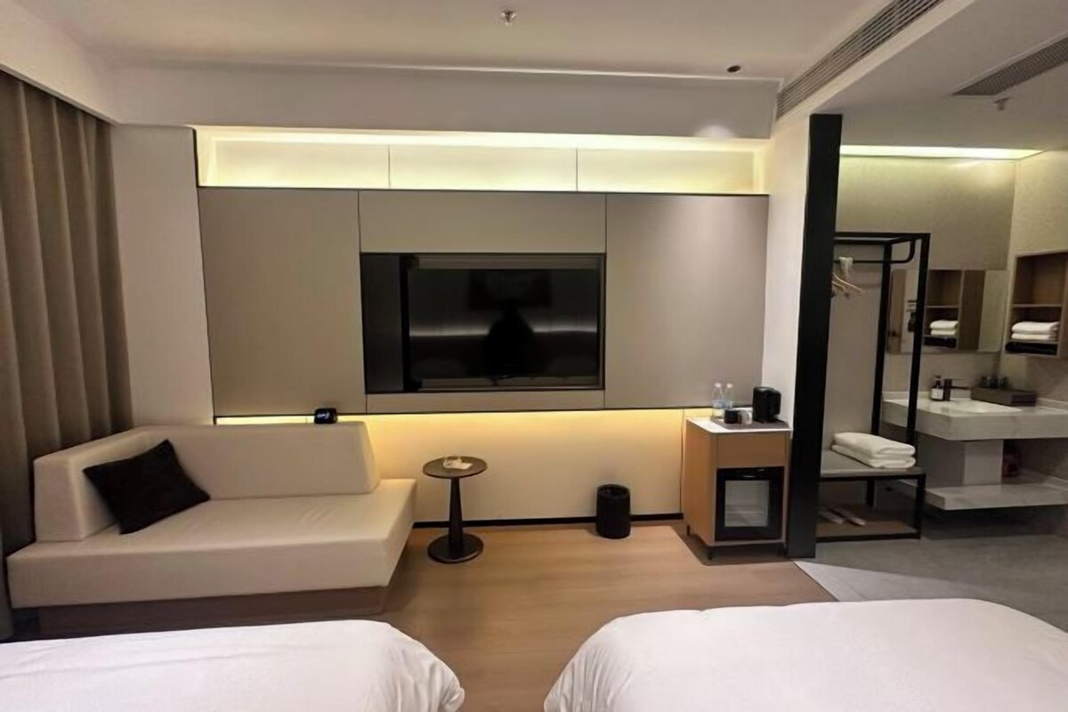 Une chambre d’hôtel avec un canapé, une télévision, une petite table, un miroir et un lit.