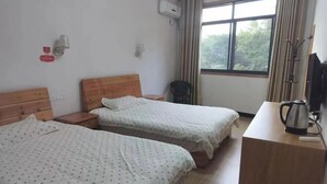 A hotel room with two beds, a wooden nightstand, a desk with a kettle, a television, and a window with curtains. - Huangshan Qiyunshan Yuehua Building Accommodation (Xiuning)