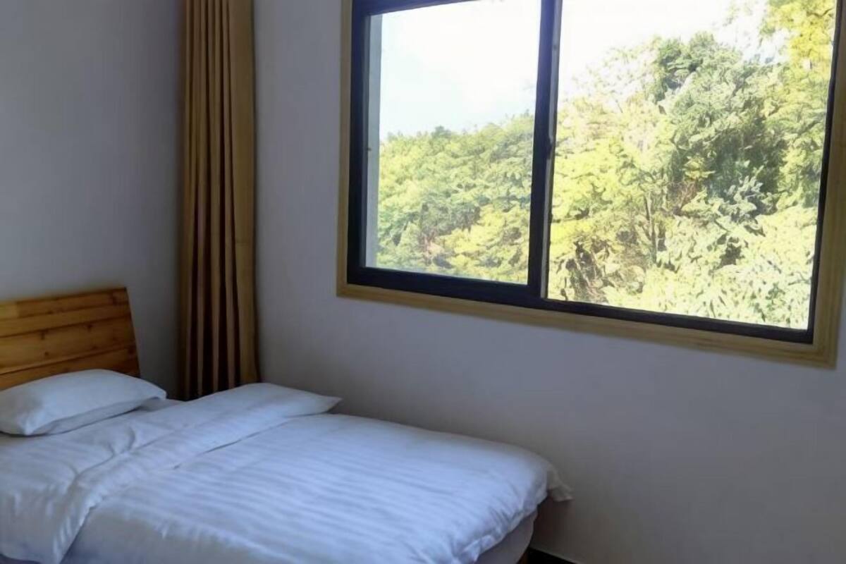 Um quarto com cama, janela e vista para árvores.