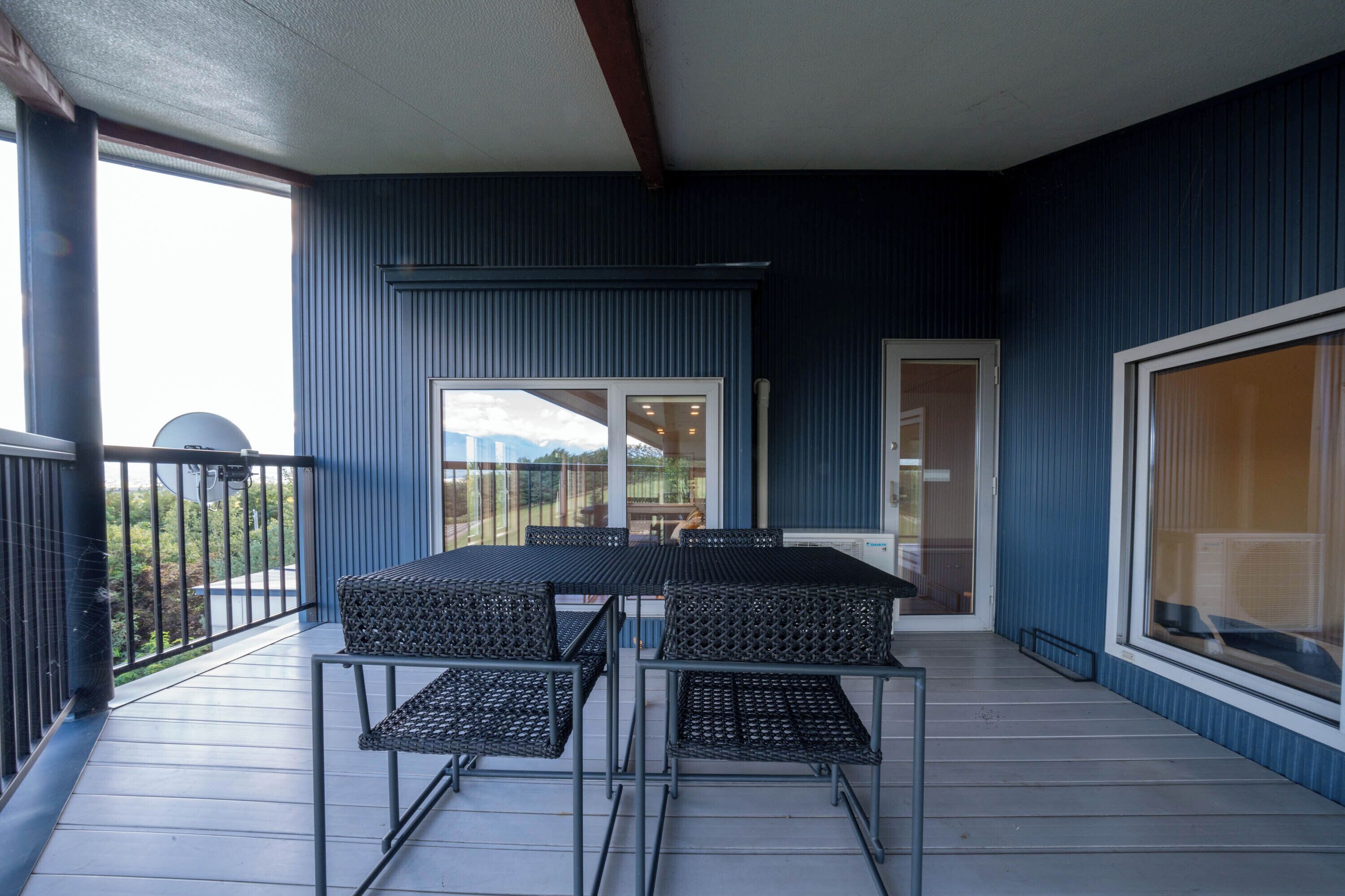 Un balcon avec une table et des chaises, une porte-fenêtre coulissante et une vue sur l’extérieur.